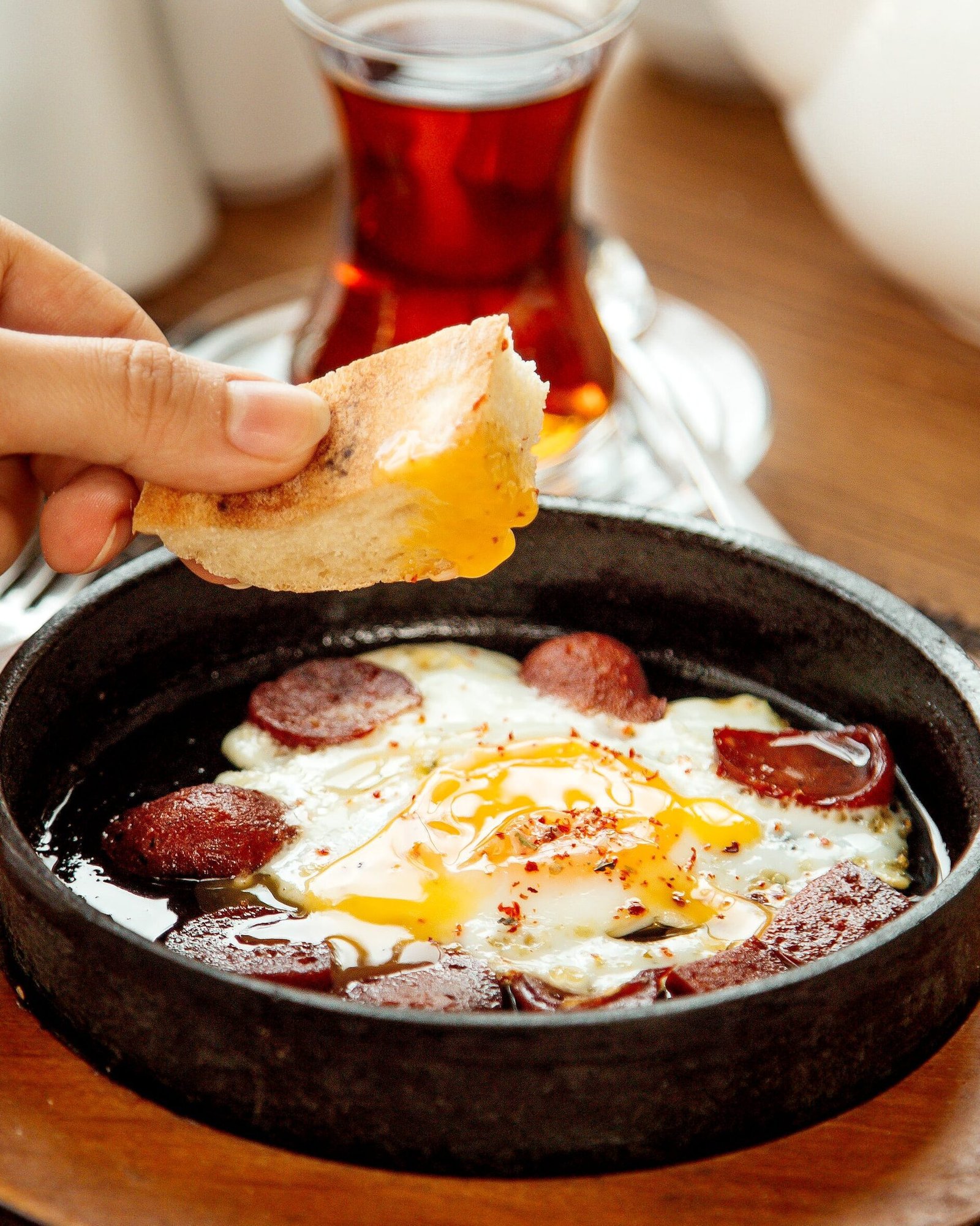 woman-dipping-bread-into-egg-sausage-dish-min Menemen turc fait maison pour petit-déjeuner à Schaerbeek